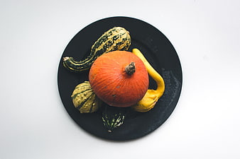 Top view of decorative gourds and pumpkin on black plate