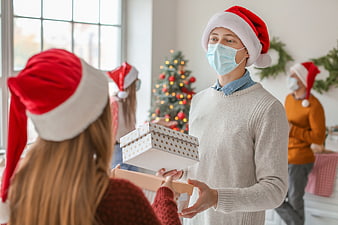 Family exchanging Christmas gifts while wearing face masks