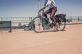 Man Cycling on Urban Path with Pannier Bags