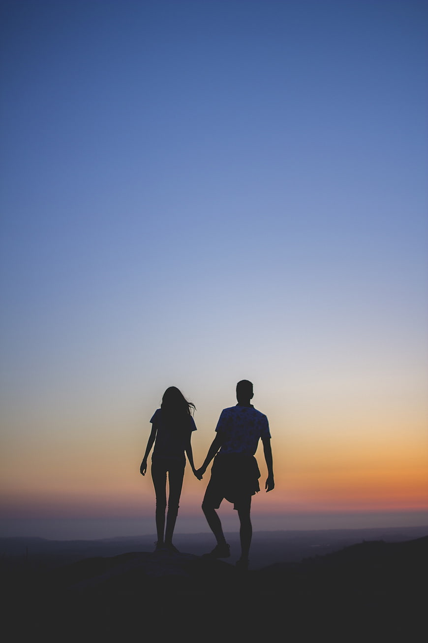Silhouette of couple holding hands at sunset