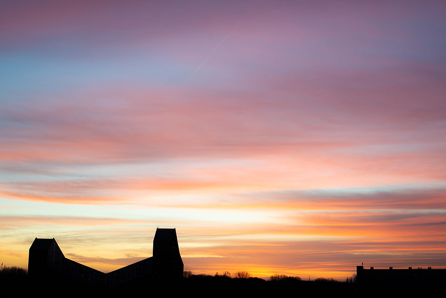 Silhouette of buildings against a vibrant sunset sky