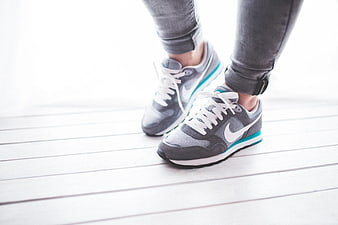 Close-up of gray Nike sneakers on white wooden floor