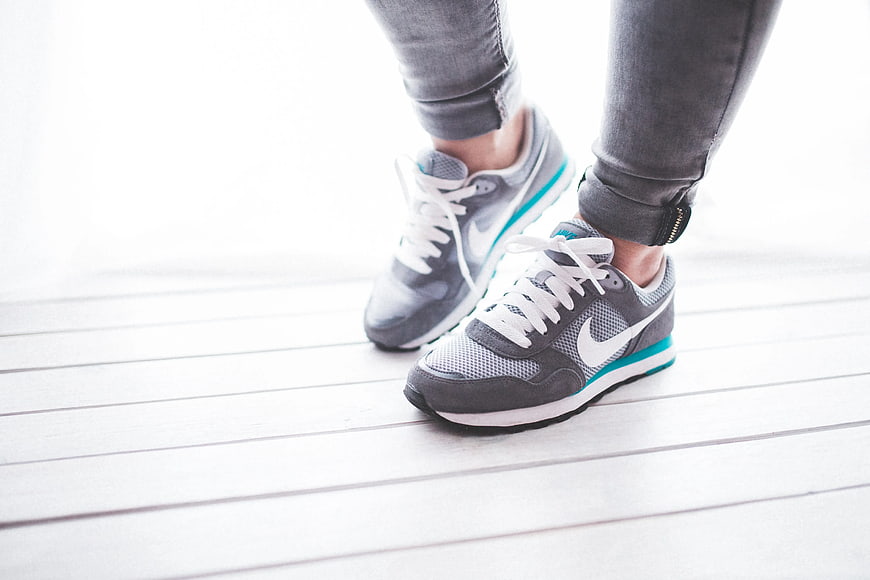 Close-up of gray Nike sneakers on white wooden floor