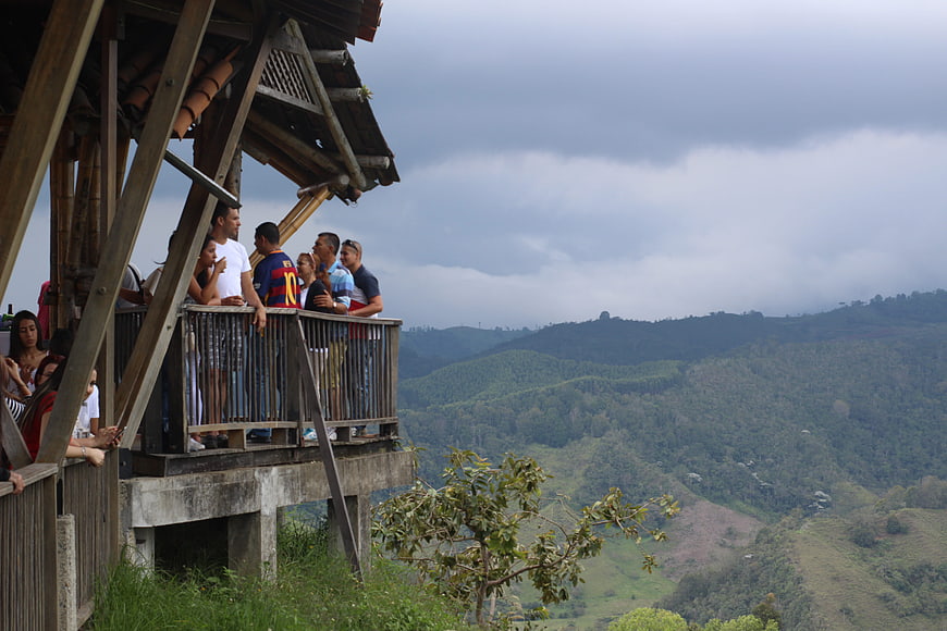 Tourists on wooden balcony overlooking Salento coffee region hills