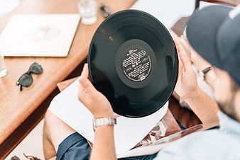 Man holding vinyl record album on wooden table