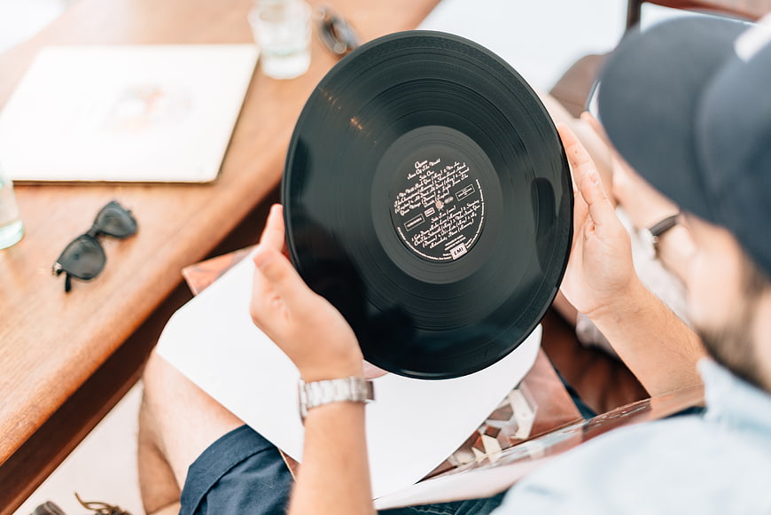 Man holding vinyl record album on wooden table