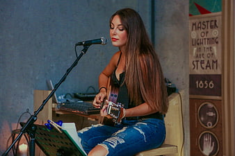 Female singer performing acoustic guitar and vocals in intimate venue
