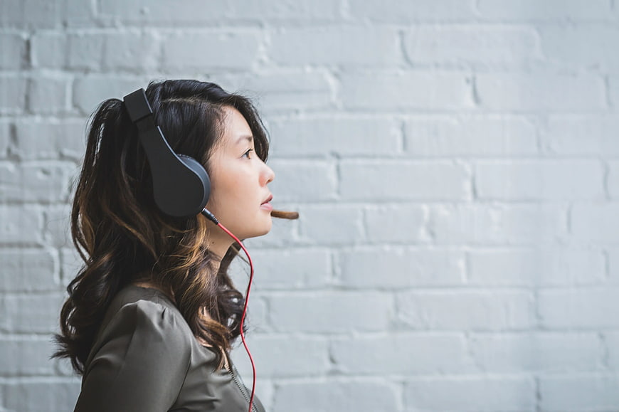Woman Wearing Headset Against White Brick Wall