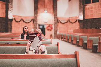 Child Hiding Behind Christmas Book in Church Pew
