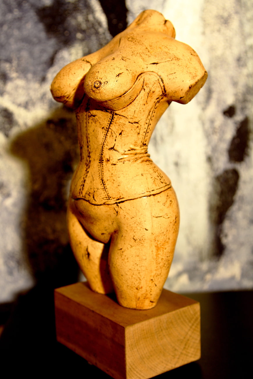 Carved wooden female torso sculpture on a wooden block