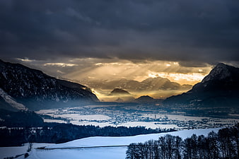 Dramatic Winter Alpine Valley Landscape With Sunbeams Breaking Through Dark Clouds