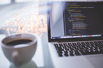 Laptop with code and coffee cup on desk