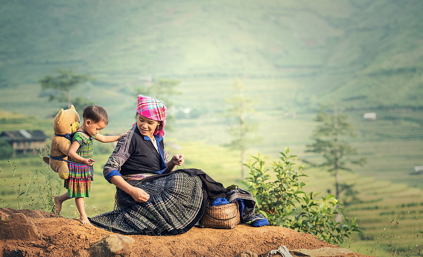Mother and Child in Traditional Clothing with Teddy Bear