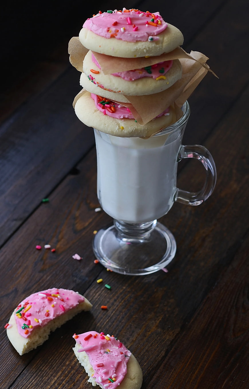 Stacked Sugar Cookies with Pink Frosting and Sprinkles on Milk Glass