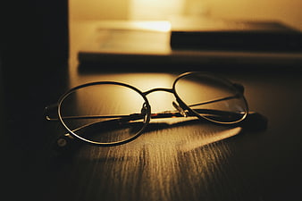 Vintage eyeglasses on wooden desk with warm lighting