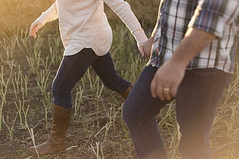 Couple Holding Hands Walking Through Golden Field
