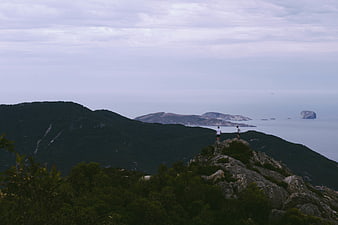Two Hikers on Rocky Mountain Peak Overlooking Sea