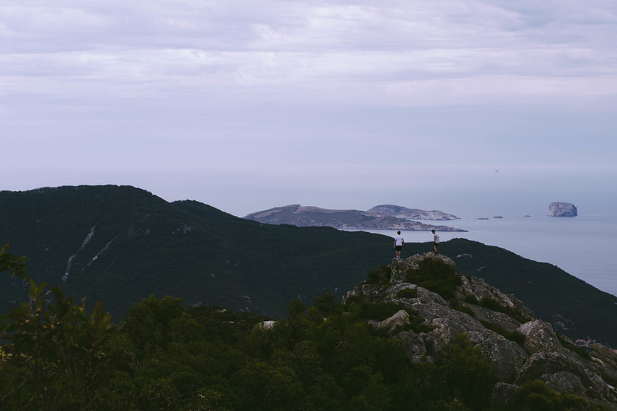 Two Hikers on Rocky Mountain Peak Overlooking Sea