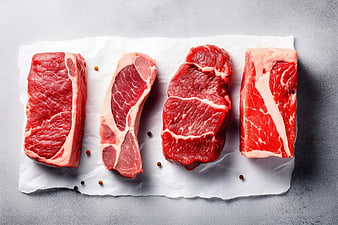 Top View of Four Raw Beef Steak Cuts on White Paper