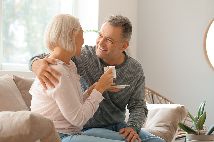 Happy Senior Couple Laughing Together on Sofa at Home
