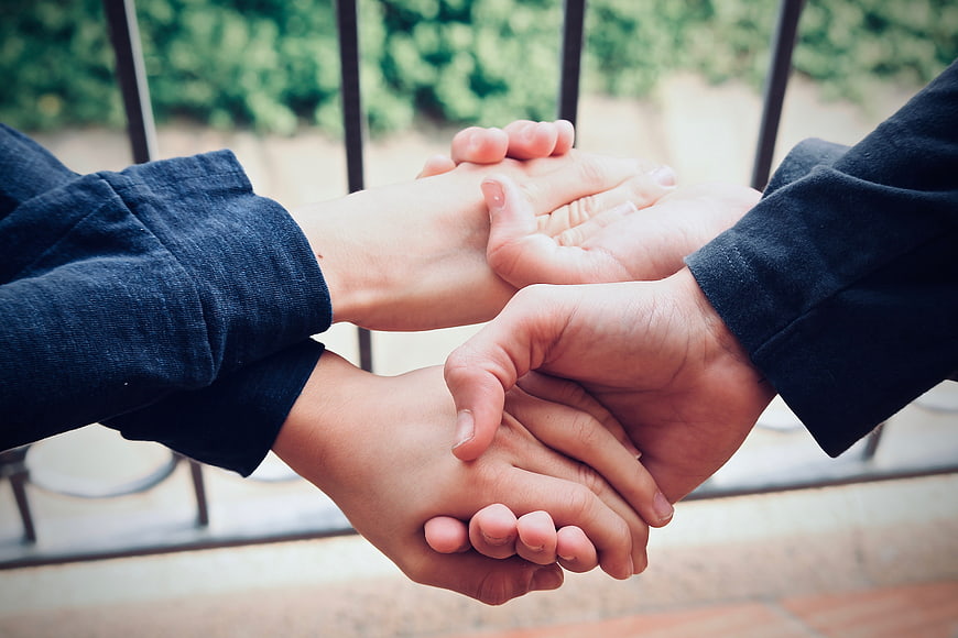 Close-up of multiple hands stacked together outdoors