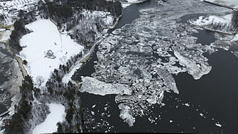 Aerial view of ice floes floating on a dark river in winter