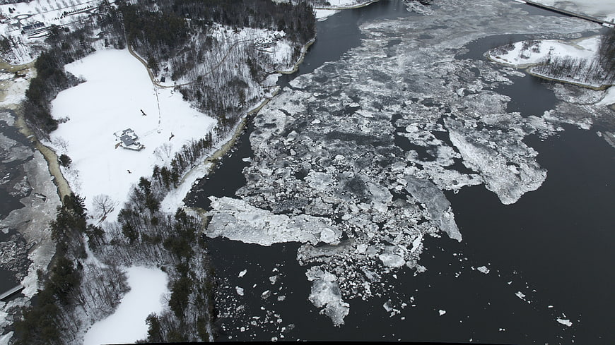 Aerial view of ice floes floating on a dark river in winter