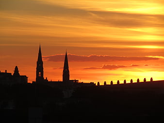 Silhouette of church spires against vibrant orange sunset sky