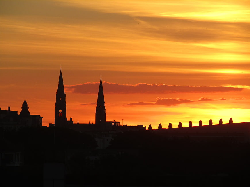 Silhouette of church spires against vibrant orange sunset sky