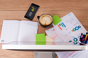 Flat lay of office desk with coffee, charts, and smartphone