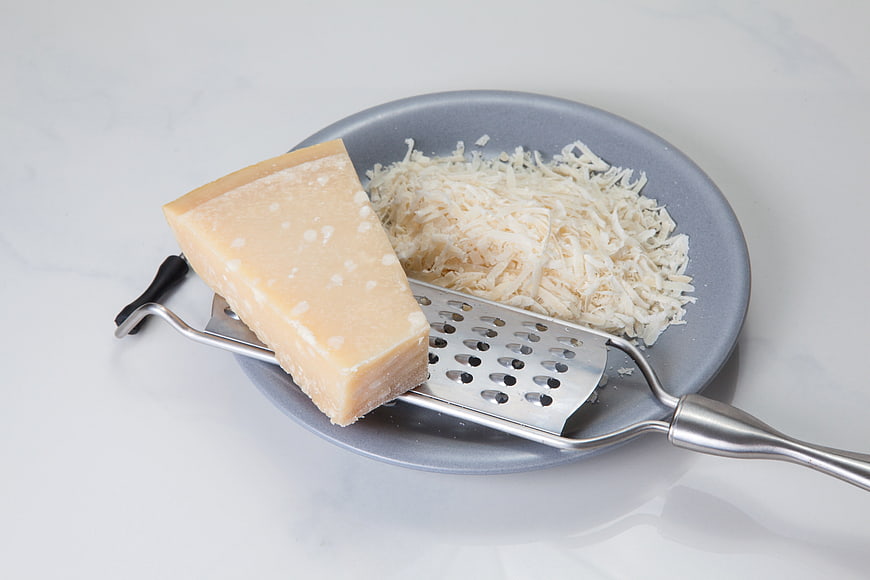 Parmesan Cheese Wedge With Grater And Shreds On Plate