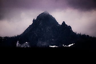 Dark moody mountain peak shrouded in mist and clouds