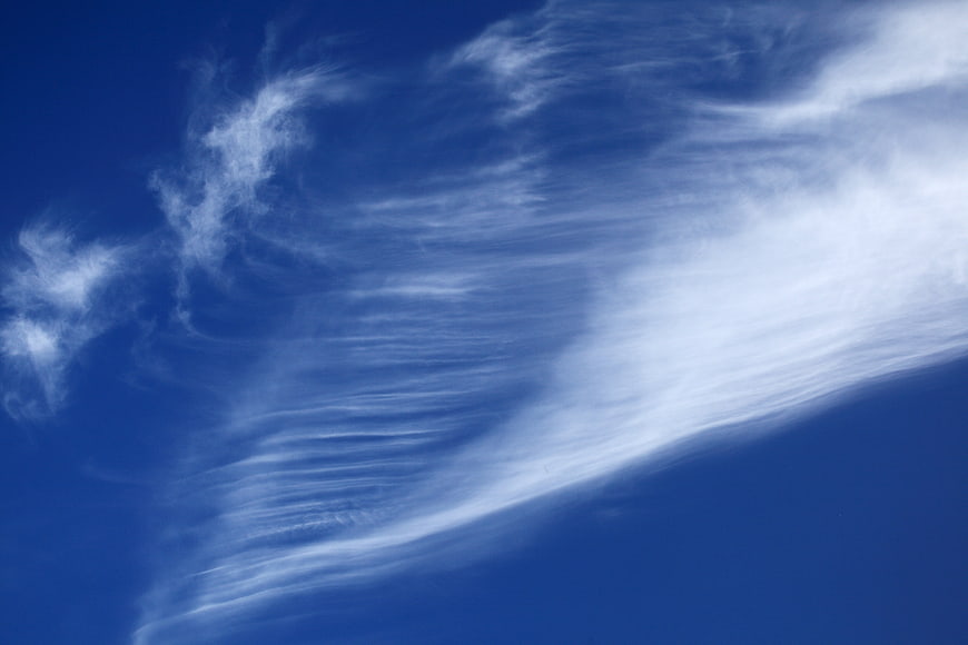 Streaky white cirrus clouds against deep blue sky
