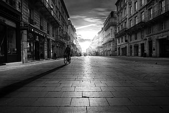 Cyclist on Empty Cobblestone Street in Black and White