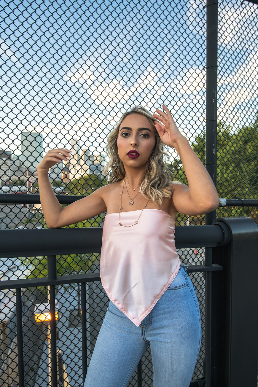 Stylish Blonde Woman in Pink Top on Urban Bridge