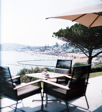 Outdoor cafe table overlooking crowded beach and ocean