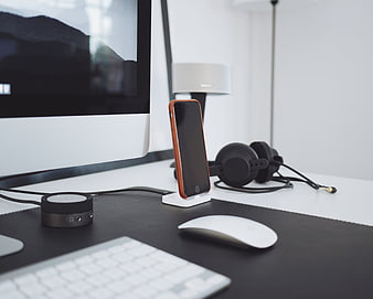 Modern minimalist workspace with smartphone, headphones, and computer
