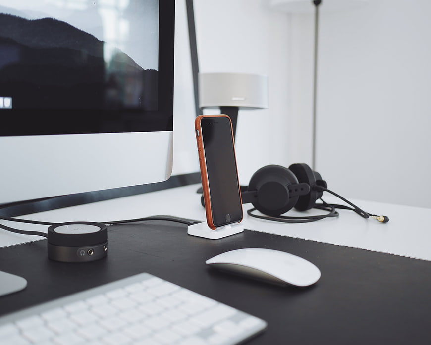 Modern minimalist workspace with smartphone, headphones, and computer