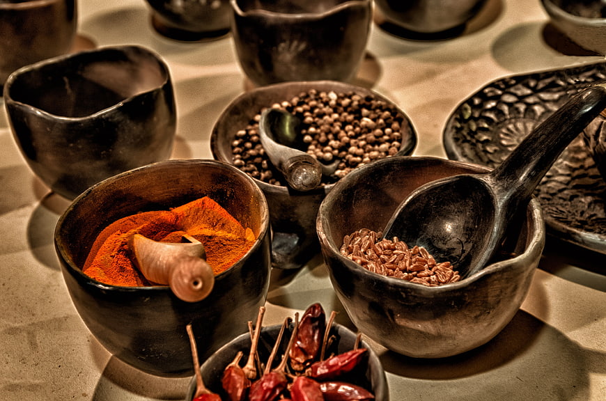 Rustic wooden bowls filled with colorful spices and dried chilies