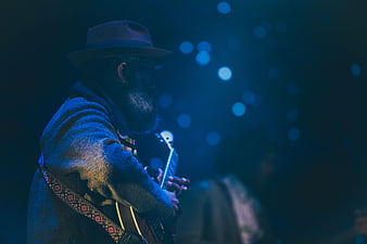 Musician playing guitar on stage with blue bokeh lights
