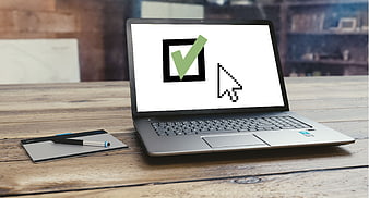 Laptop displaying digital consent checkbox and cursor on wooden table