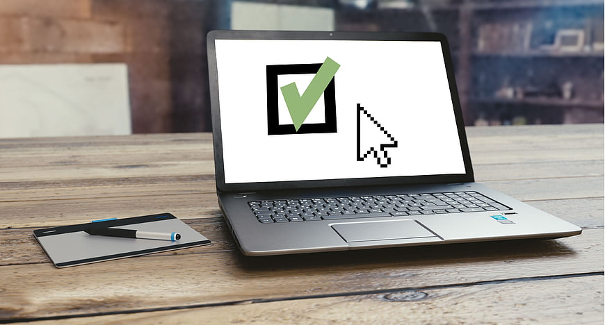 Laptop displaying digital consent checkbox and cursor on wooden table