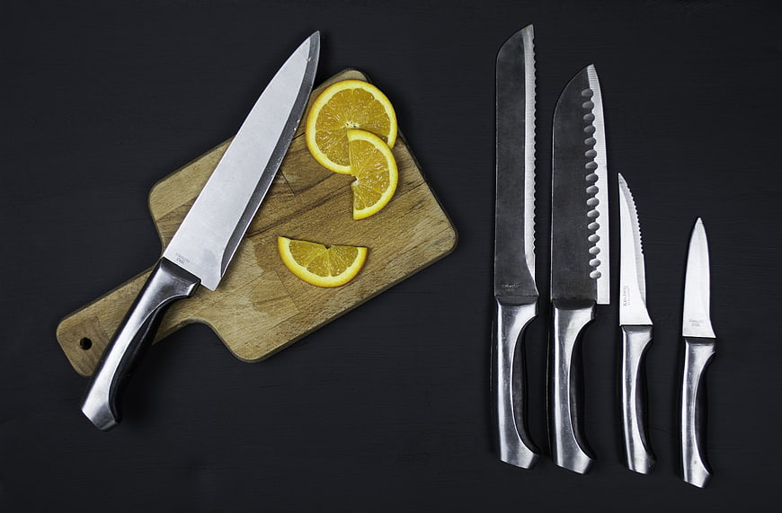 Kitchen knife set with orange slices on wooden board