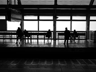 Silhouettes of people waiting on a train station platform