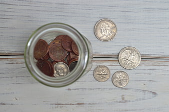 Glass Jar Filled With US Coins On White Wooden Surface