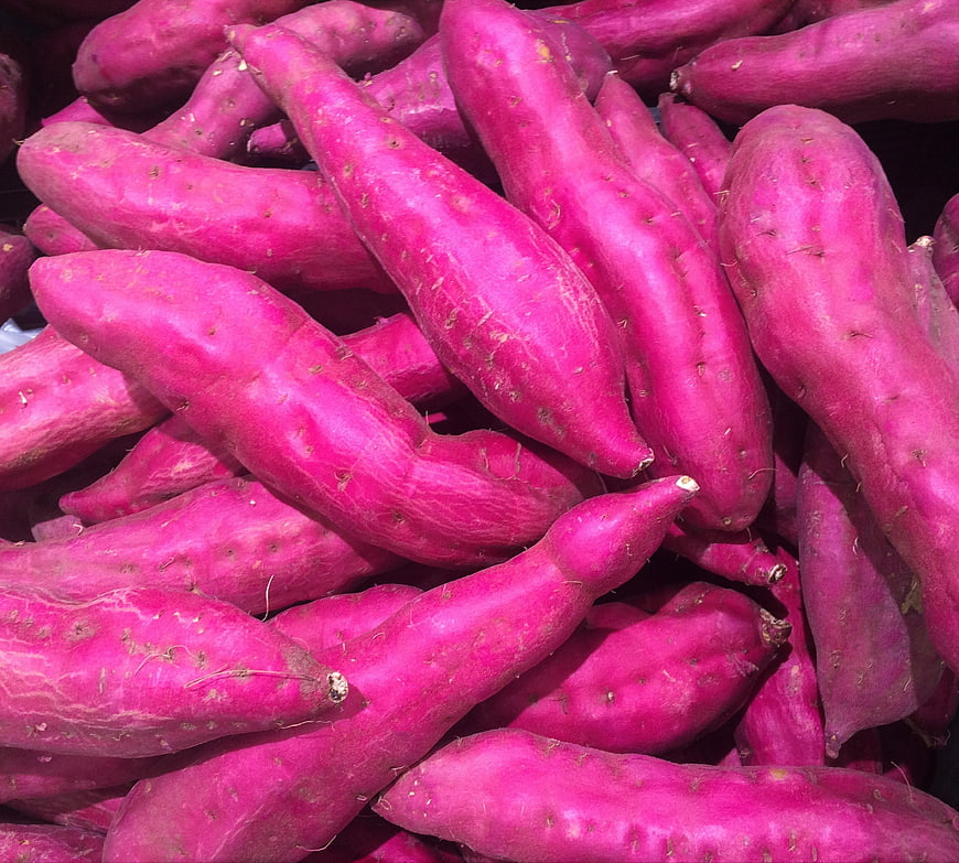 Vibrant Purple Sweet Potatoes Piled in Market Display