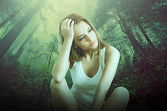 Thoughtful young woman sitting in a misty green forest