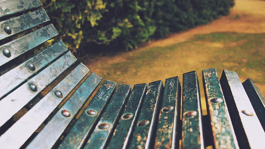 Close-up of weathered green park bench slats