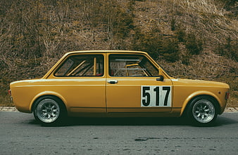 Yellow vintage rally car with number 517 on asphalt road