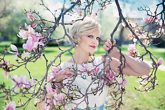 Blonde Woman Posing Among Pink Magnolia Blossoms